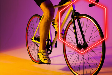 Illuminated hexagon over low section of caucasian male athlete riding bike on purple background - Powered by Adobe