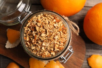 Jar of dried orange zest seasoning and fresh fruits on wooden table, flat lay