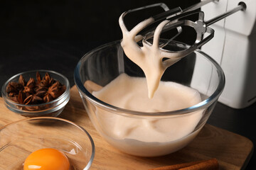 Different ingredients and mixer on black table. Cooking delicious eggnog