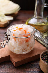 Glass jar of tasty sauerkraut on wooden table