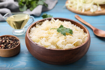Bowl of tasty sauerkraut on light blue wooden table, closeup