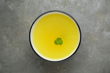 Delicious chicken bouillon with parsley on grey table, top view