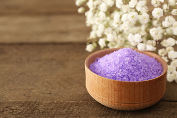 Obraz na płótnie Canvas Purple sea salt and beautiful flowers on wooden table, closeup. Space for text