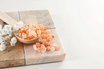 Fototapeta na wymiar Orange sea salt and beautiful flowers on white table, closeup. Space for text