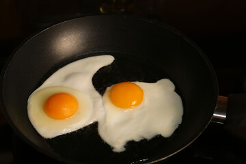 Cooking eggs for breakfast in frying pan on cooktop