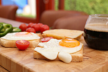Tasty toasts with fried eggs and tomatoes on wooden table indoors, closeup
