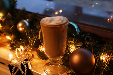 Glass of delicious hot cocoa and Christmas decoration on windowsill