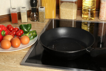 Many eggs and vegetables near frying pan on wooden countertop in kitchen