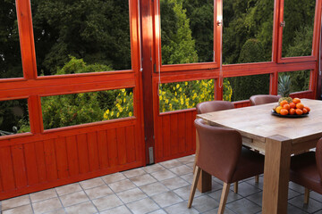 Wooden table with fruits and stylish chairs on terrace