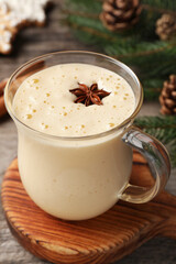 Glass of delicious eggnog with anise star on wooden table, closeup