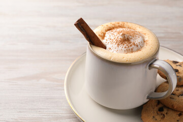 Cup of delicious eggnog with cinnamon and cookies on wooden table, space for text