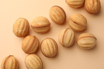 Homemade walnut shaped cookies with condensed milk on beige background, flat lay