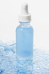 Blue jar with a pipette. Against the background of water drops. Blue background. Facial serum, tonic, moisturizing, freshness.