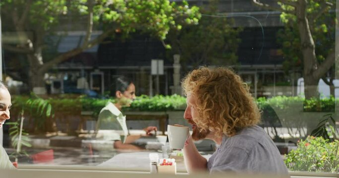 Happy diverse couple drinking coffee and talking at a table in a cafe
