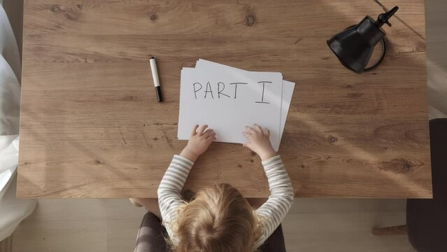 Top down view of child at table, who takes paper with inscription part 1, crumple it and throw it away. Part 2 and part 3 - inscriptions on following papers. three parts of online education or series.