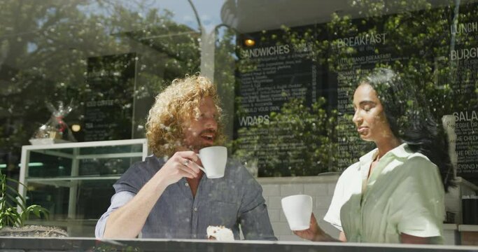 Happy diverse couple drinking coffee and talking in cafe