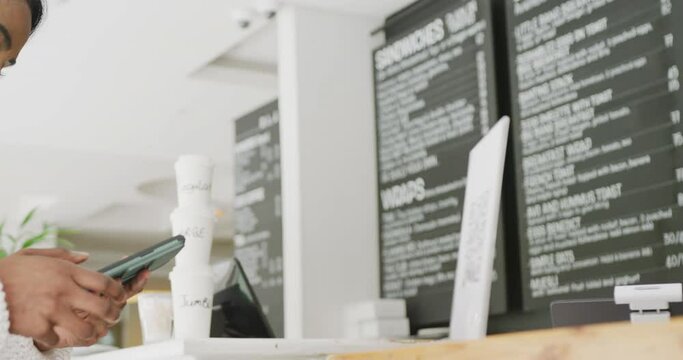 Happy biracial woman scanning qr code with smartphone in cafe