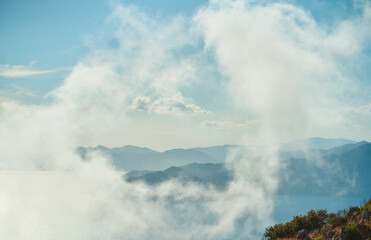 Obraz premium Scenic landscape of mountains in clouds and rocky steep coast of the Aegean Sea in Turkey.