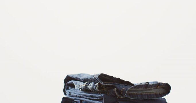 Close up of folded jeans with different shades on white background with copy space