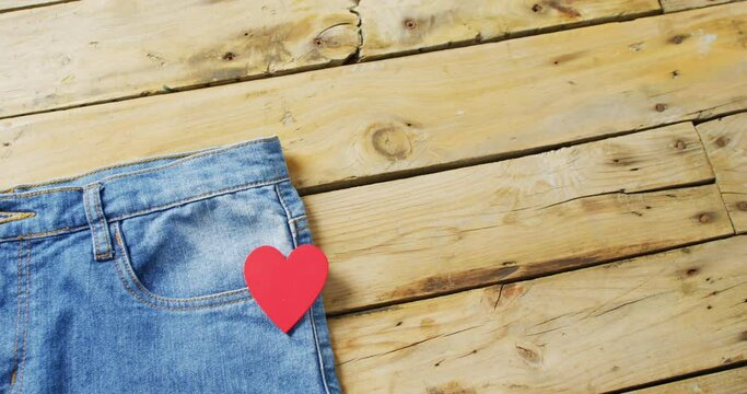 Close up of jeans with red heart on wooden background with copy space
