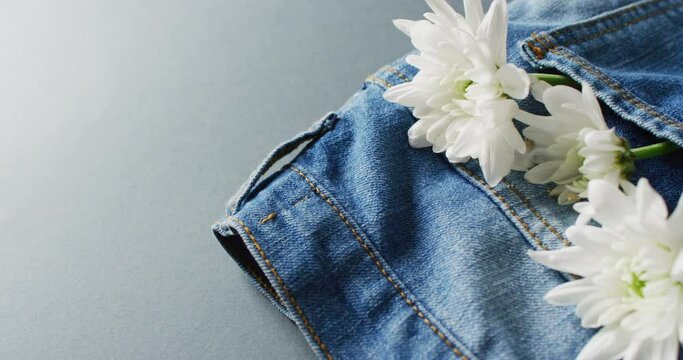 Close up of jeans with white flowers on grey background with copy space