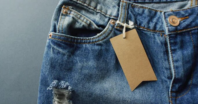Close up of jeans with tag on grey background with copy space
