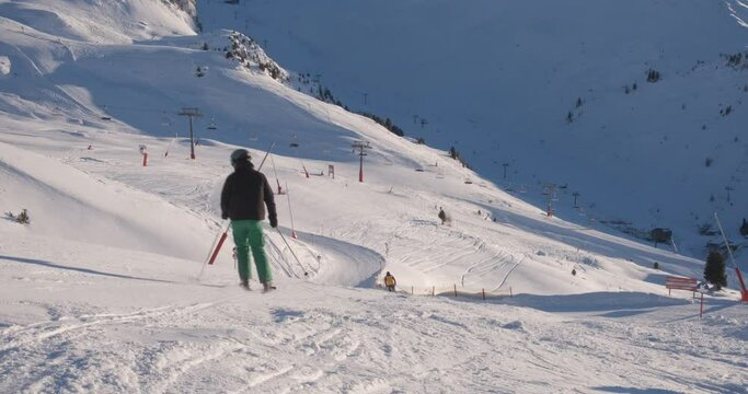 Skiers on piste at Ischgl ski resort, Austria, ski down towards the valley in the evening. Winter, vacation, snow, slope.