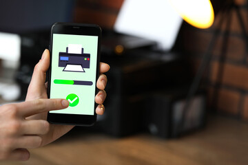 Man using printer management application on mobile phone indoors, closeup and space for text