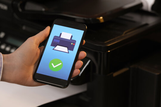 Man using printer management application on mobile phone indoors, closeup and space for text