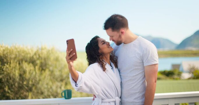 Couple, selfie and people kiss in the morning on vacation or holiday at a hotel or on the balcony. Interracial, relax and lovers taking picture or photo with peace gesture and enjoying quality time