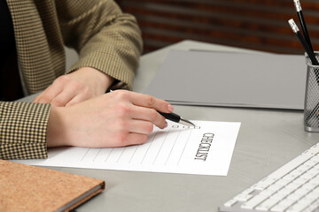 Woman filling Checklist at light grey table, closeup