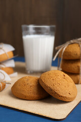 Tasty oatmeal cookies and glass of milk on blue wooden table, closeup