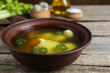 Delicious chicken bouillon with parsley, carrot and eggs on wooden table, closeup