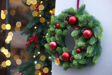 Beautiful Christmas wreath hanging on building wall outdoors, space for text