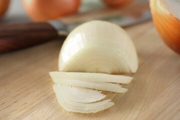 Partially sliced onion on wooden board, closeup