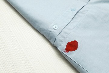 Shirt with stain of red ink on wooden table, closeup