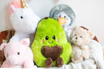 the bunch of stuffed toys with avocado plush toy in the center