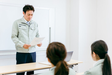 Obraz premium 工場・会社・オフィス・会議室で会議・セミナー・勉強会の講師をするエンジニア・技術者・作業員の男性