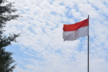 Indonesian Flag, Red and White, waving in the wind with blue sky background