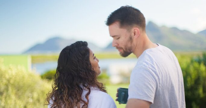 Couple, vacation and kiss with coffee in morning, lake and mountain for hug, romantic honeymoon and nature. Man, woman and love for start, sunshine and freedom with care on outdoor holiday at lodge