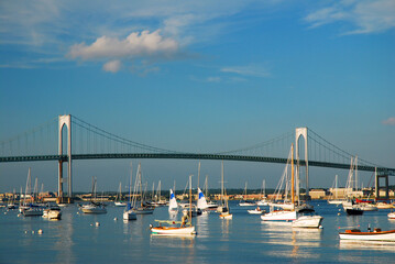 The Newport Pell Bridge spans Narragansett Bay, crossing in front of sailboats and recreation boats of the craggy coast of Rhode Island