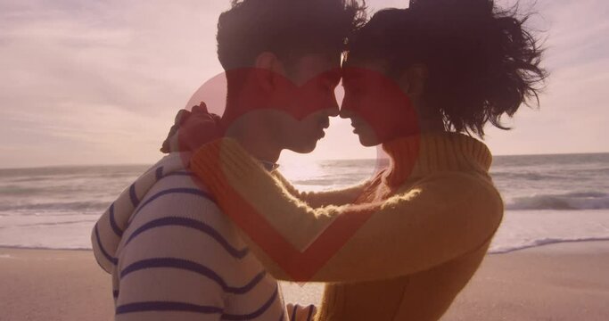 Animation of red heart over couple in love embracing on beach