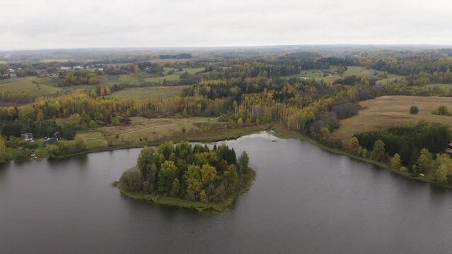 Drone of lonely island with a forest in the middle of a lake (autumn)
