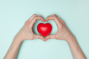 Fototapeta premium Health, medicine and charity concept - close up of female hands with small red heart. Flat lay.