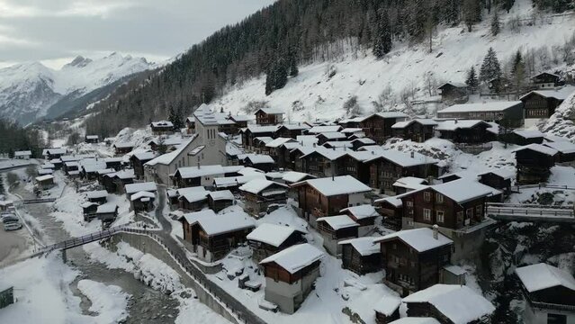 Ein idyllisches Schweizer Bergdorf im Winter. Blatten im L&ouml;tschental in der Schweiz. Die Kirche ist mitten im Dorf. Alles ist mit Schnee bedeckt.