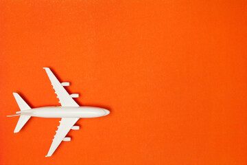 Airplane model. White plane on orange background. Travel vacation concept. Summer background. Flat lay, top view, copy space.