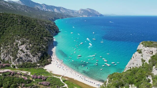 Boats and Tourist People at Cala Luna Beach, Baunei Coast, Sardinia, Italy - Aerial 4k
