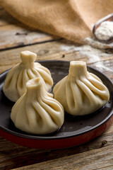 Khinkali with lamb on black plate on wooden table macro close up vertical