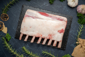 Fresh lamb rack with rosemary in black plate on wooden background, Fresh Raw lamb loin on black Background.
