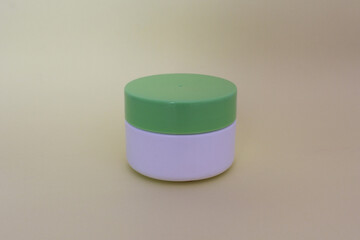 Bote para crema facial en color blanco con tapa verde. 